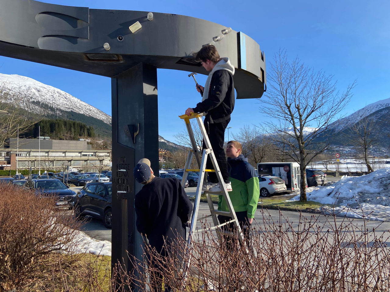 Elev i gardintrapp ved svart skulptur
