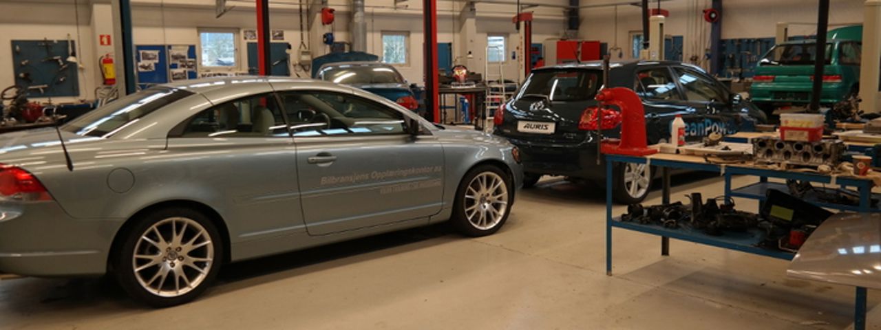 Bilete viser bilar som står plassert inne i ein verkstadshall